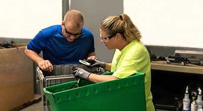 A man and woman looking into a recycling bin