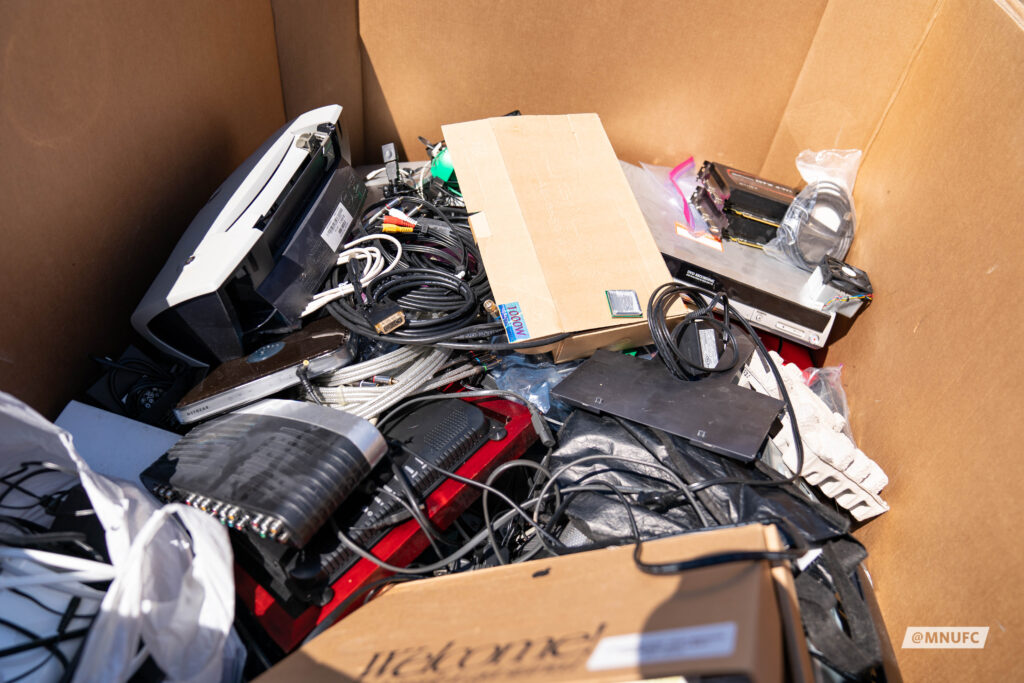 Pile of old electronics in a cardboard box.