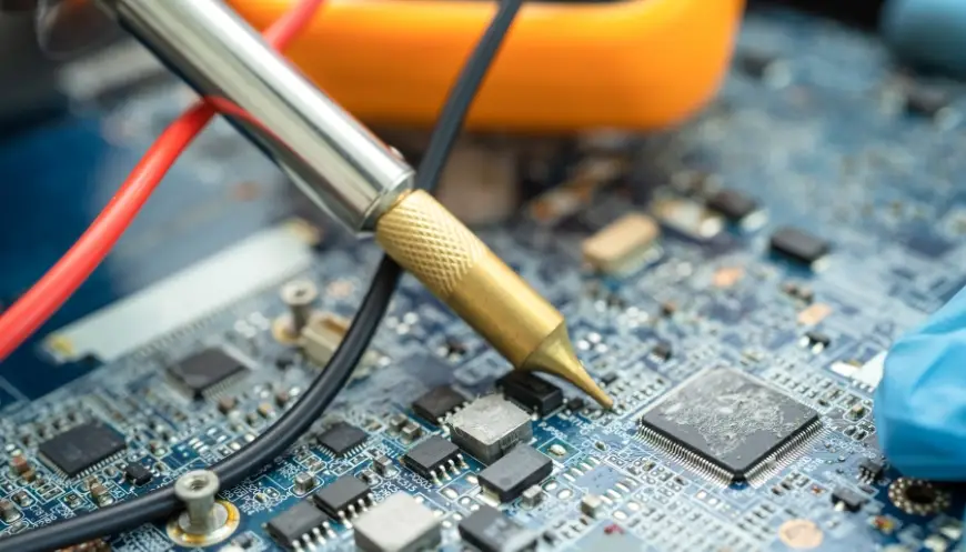 Close-up of a technician using a soldering iron on a hard disk drive during electronics refurbishment.