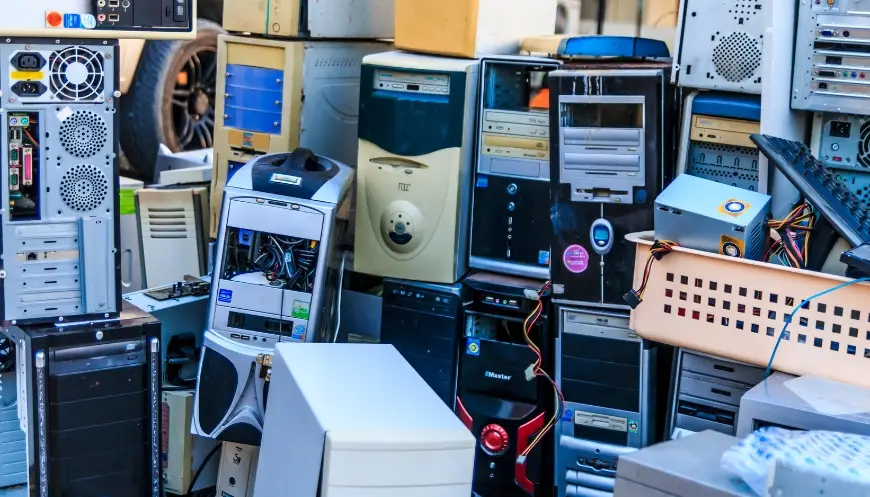A pile of old computer towers and electronic devices stacked for e-waste recycling at a certified facility.