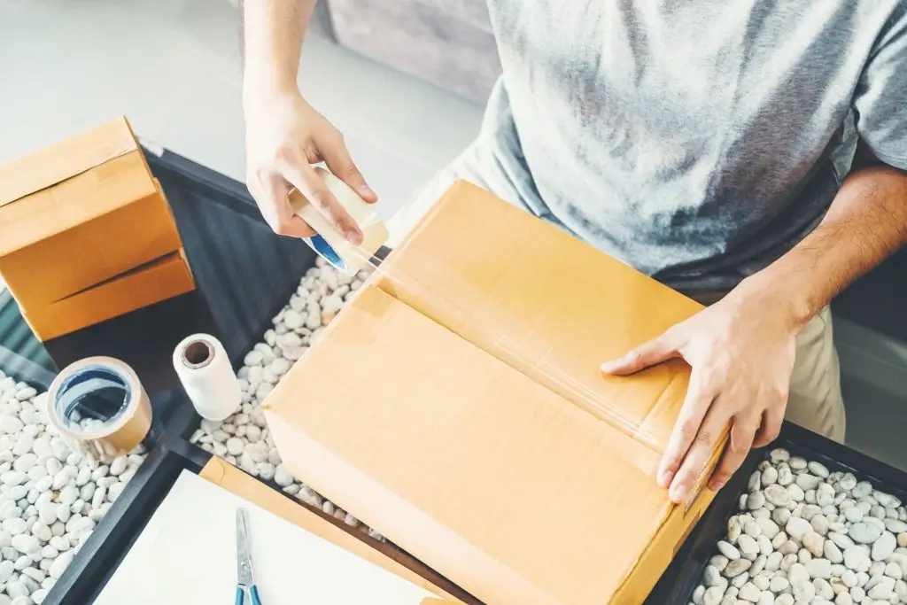 shown by a worker sealing boxes amid packaging materials.