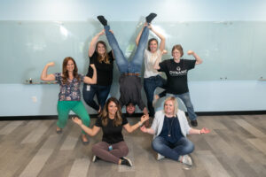 Team members at Dynamic Lifecycle Innovations pose in superhero positions.