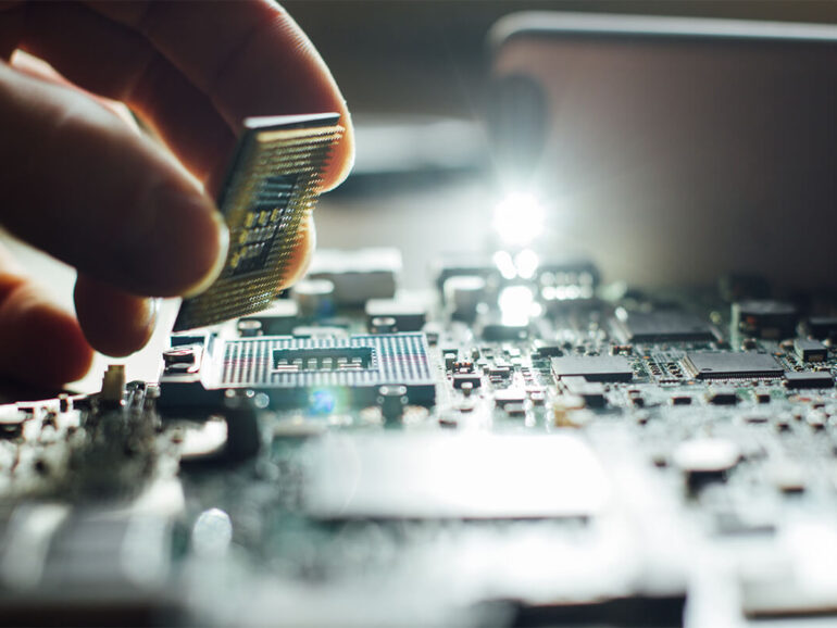 A person laying down a processor card on the motherboard.