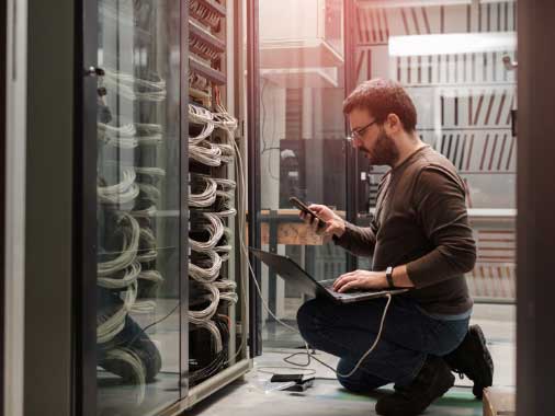 An IT worker testing connections in a server room.