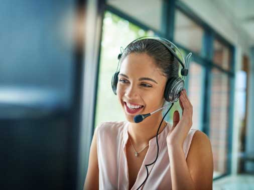 A happy customer service woman on a call at her computer.