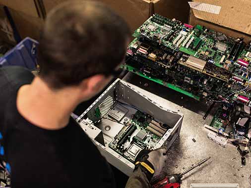 Dynamic Lifecycle Innovation technician reviewing the electronic components in a recycled computer tower.