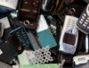 Small IT Assets, including vintage cell phones and computer chips are piled in a recycling bin.