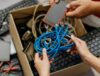 People putting old electronics into a cardboard box to simplify the recycling process.