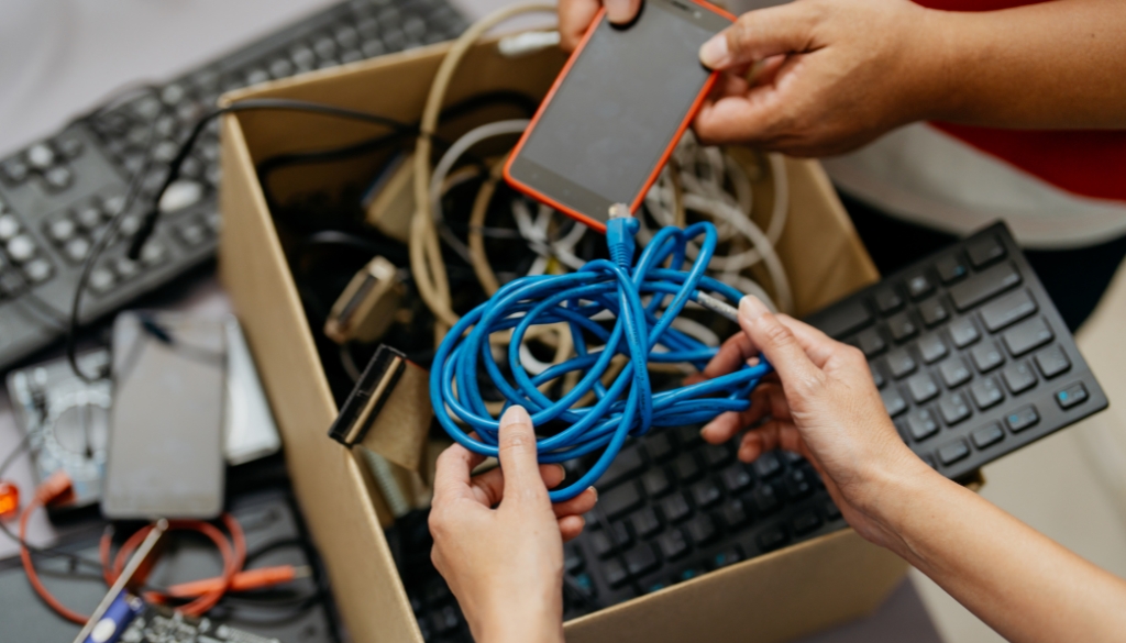 People putting old electronics into a cardboard box to simplify the recycling process.