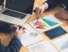 Two men in a business meeting looking at reporting charts. Dynamic Lifecycle Innovations ESG Reporting and Performance.