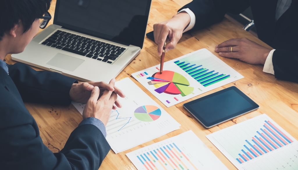 Two men in a business meeting looking at reporting charts. Dynamic Lifecycle Innovations ESG Reporting and Performance.