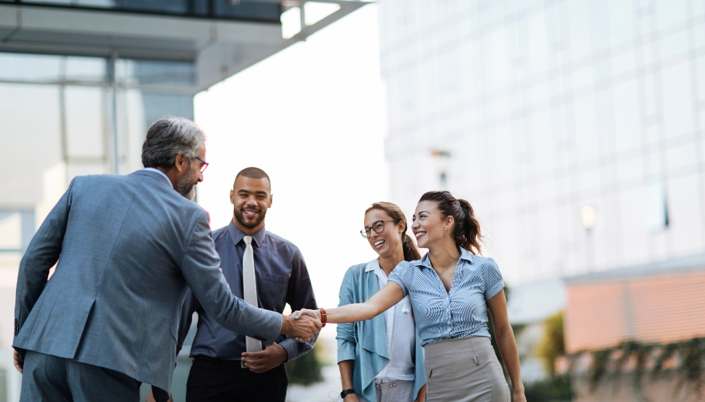 Business partners demonstrating service excellence while shaking hands outside of an office building.