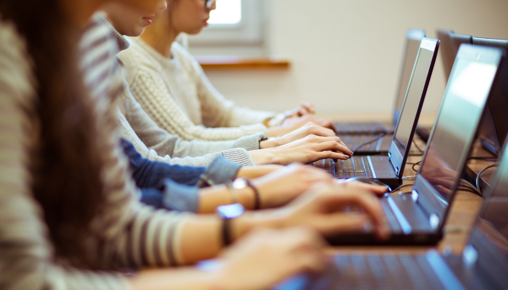 College students working on laptops in a classroom.