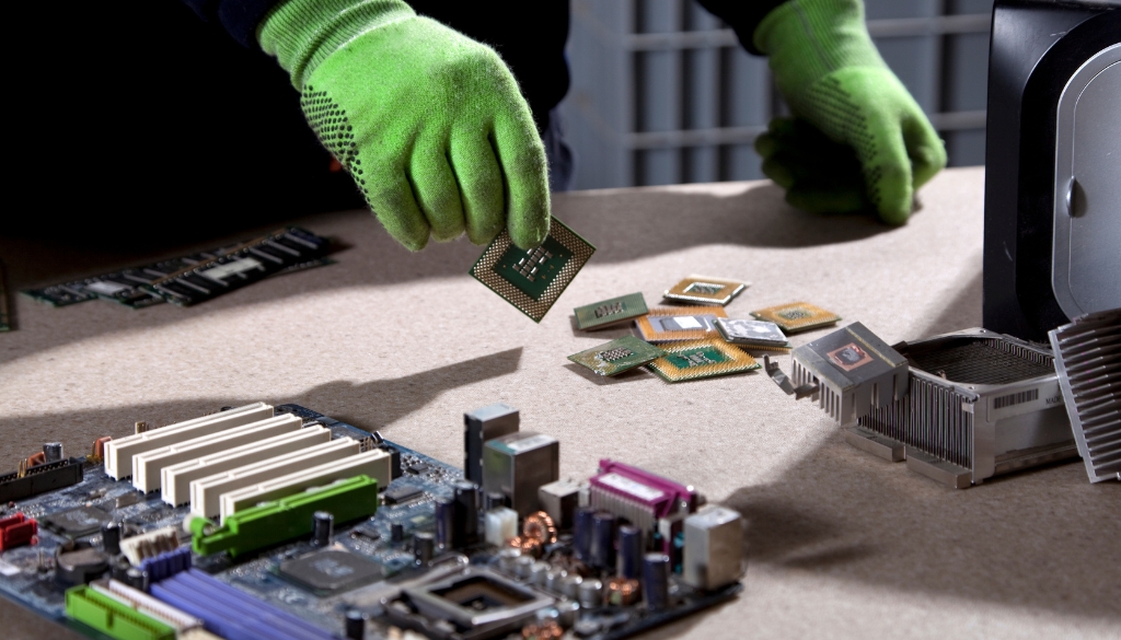 An ITAD worker pulling multiple computer parts & components from an old, recycled computer.