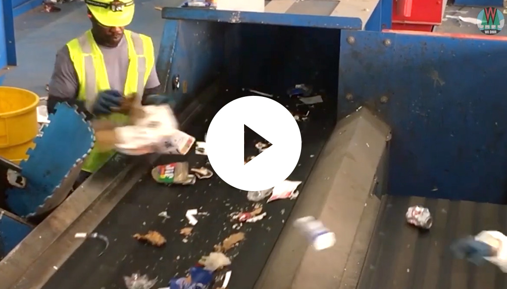 A Dynamic Lifecycle Innovations worker placing items on a recycling conveyor belt.