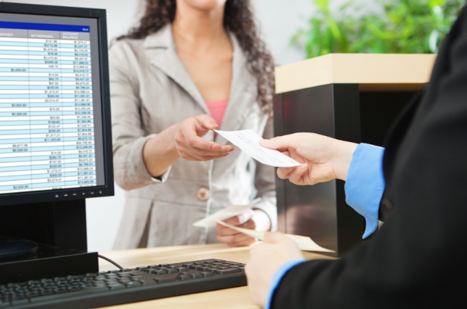 Customer hands a bank teller a check.