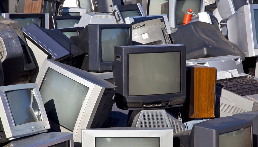 Vintage televisions stacked in a pile.