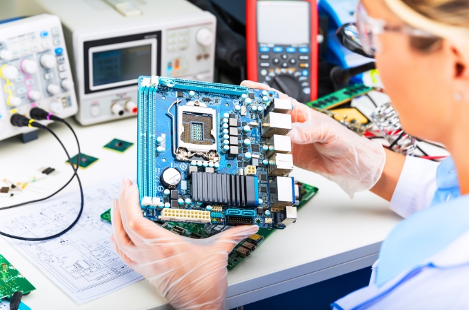 An ITAD worker reviewing a motherboard for recyclable parts.